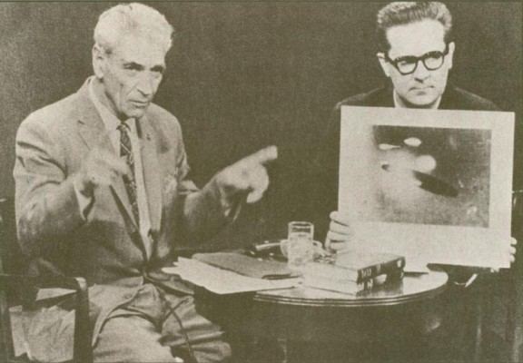 Adamski à un interview, avec une photo prise par lui de vaisseau-mère en forme de cigare.