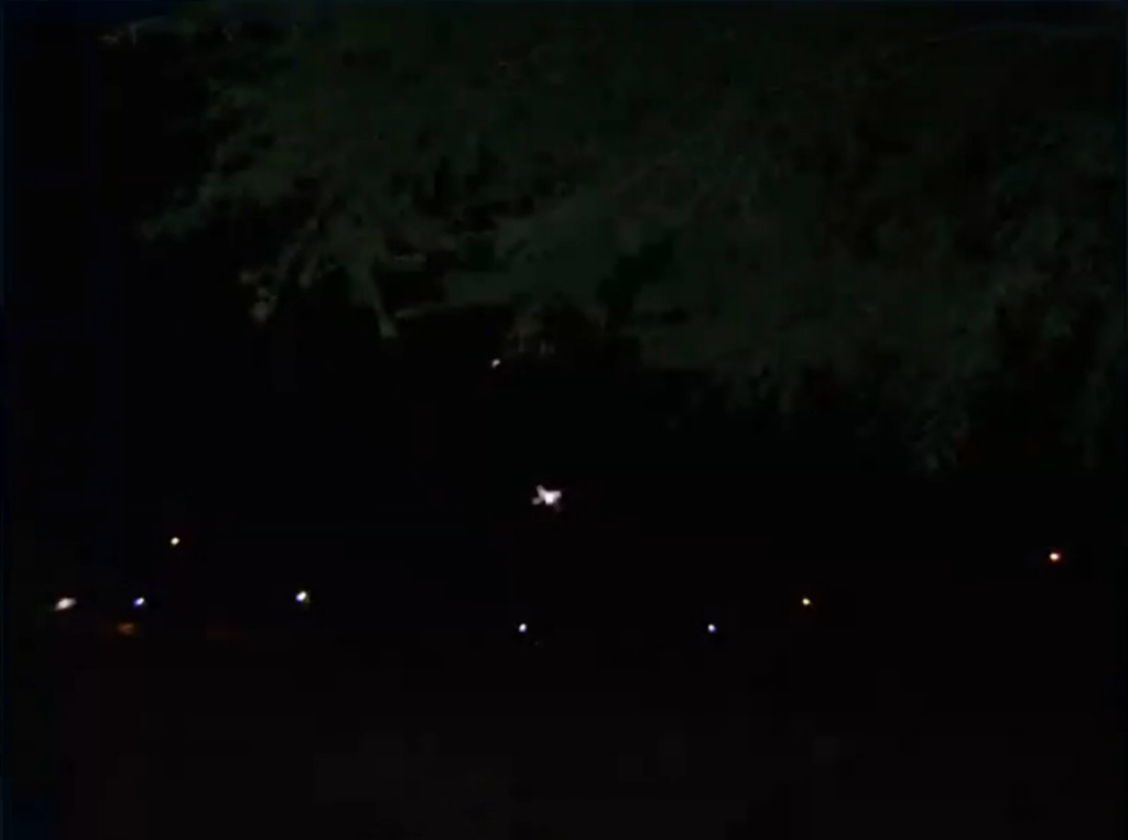 Photo du ciel de nuit prise par José Yaguana depuis son lieu de résidence. En bas une rangée de lampadaires, dans le ciel plus haut, un objet lumineux large et un plus petit objet lumineux plus haut encore. Ces deux objets sont des vaisseaux de Ectom.